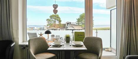 A dining area with two chairs, a table, and a view of a coastal landscape.