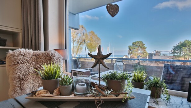 A cozy room with a view of the sea, featuring a wooden table with plants, a starfish decoration, and a rustic ambiance. - Seetempel Appartement 27 (Scharbeutz)