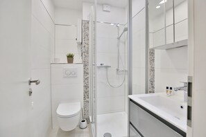 A modern bathroom with a toilet, shower, and sink. - Seetempel Appartement 27 (Scharbeutz)