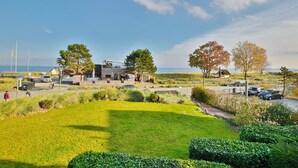 A modern building with a large lawn, a parking area, and a view of the sea. - Seetempel Appartement 27 (Scharbeutz)