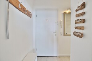 A hallway with a white door, wooden wall decor with words, and a light switch. - Seetempel Appartement 27 (Scharbeutz)