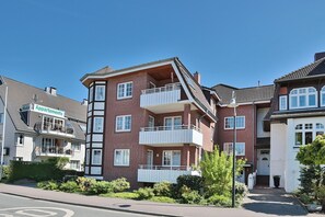 Ein mehrstöckiges Wohngebäude mit Balkonen, einem sichtbaren Schild mit der Aufschrift 'Appartments' und blauem Himmel.