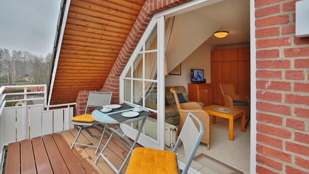 A cozy outdoor seating area with a table, chairs, and a television. - Parkblick Appartement 11 (Scharbeutz)