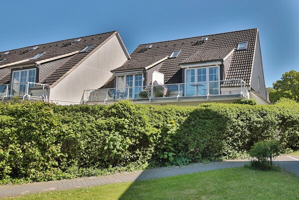A modern residential building with a sloped roof, large windows, and a balcony. - Maisonette mit Charme (Scharbeutz)