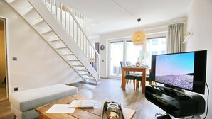 Uma sala de estar moderna com escada, área de jantar e televisão.