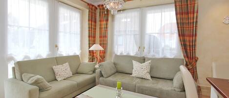 A living room with two sofas, a coffee table, and a chandelier.