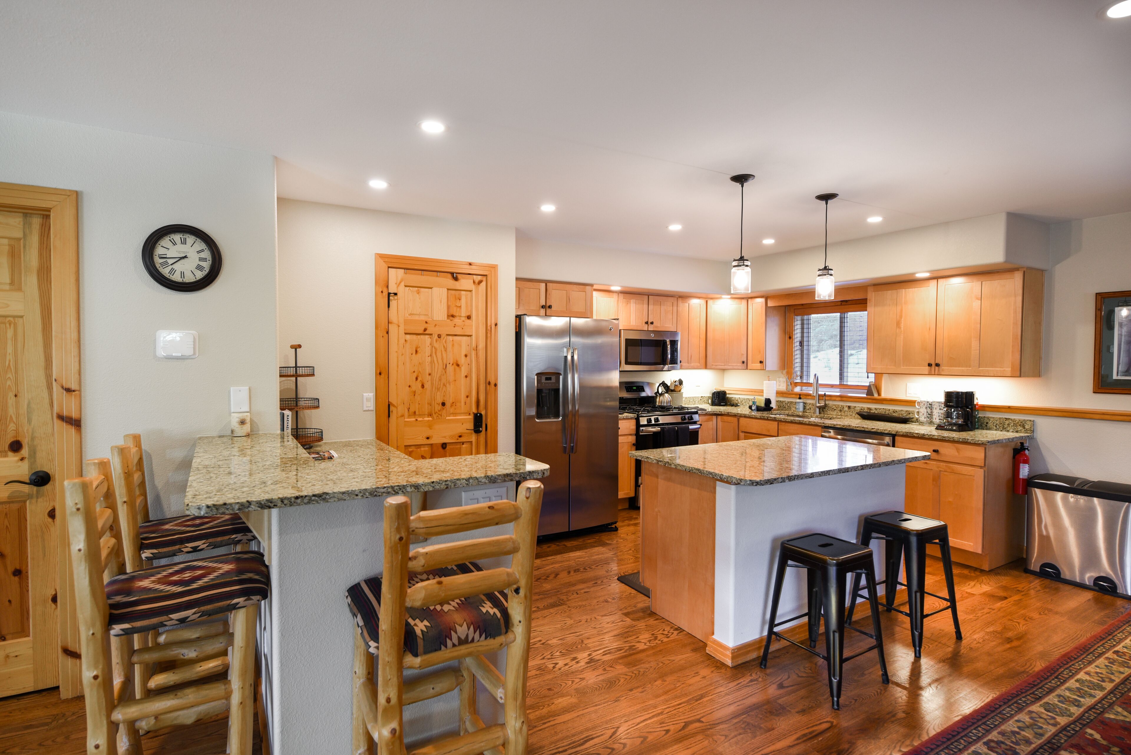 Una cocina moderna con armarios de madera, electrodomésticos de acero inoxidable y una isla central con taburetes de bar.