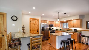 Une cuisine moderne avec des meubles en bois, des appareils en acier inoxydable et un îlot central doté de tabourets de bar.