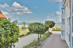 Ein gepflasterter Weg mit einem Fahrrad, eine von Bäumen gesäumte Straße und ein Gebäude mit rotem Dach.
