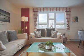 A living room with a sofa, a glass coffee table, and a lamp.