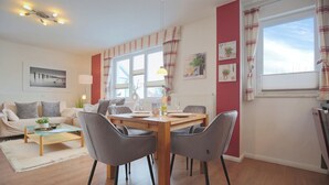 En matplats med ett träbord, fyra grå stolar och ett soffbord i glas.
