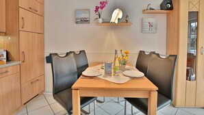 A dining area with a wooden table, black chairs, and a small shelf with decorative items. - Residenz Alte Bergstrasse Appartement 9 (Scharbeutz)