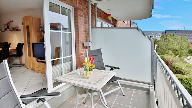 A balcony with a table and chairs, a TV, and a small kitchen area. - Residenz Alte Bergstrasse Appartement 9 (Scharbeutz)