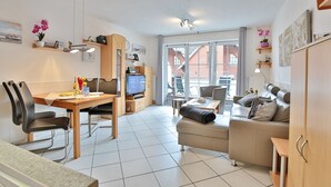 A modern living room with a dining area, a sofa, a TV, and a kitchen counter. - Residenz Alte Bergstrasse Appartement 9 (Scharbeutz)