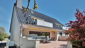 A modern house with a sloped roof, a brick exterior, and a patio area with outdoor furniture.