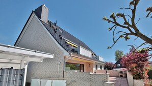 A modern house with a sloped roof, a brick exterior, and a small backyard with steps leading to a patio area.