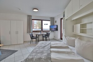 Une chambre d’hôtel avec un lit, une télévision, un bureau avec des chaises et une fenêtre avec des rideaux.