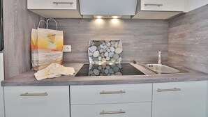 Een moderne keuken met een achterwand van steen, een roestvrijstalen spoelbak en witte keukenkastjes.