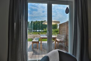 A room with a sliding glass door leading to an outdoor deck with a table and chairs. - Haus Meeresbrise Appartement 1 (Haffkrug)
