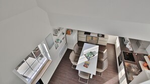 A modern kitchen with a dining area, white cabinetry, and a window. - Parkdomizil Appartement 9 (Scharbeutz)