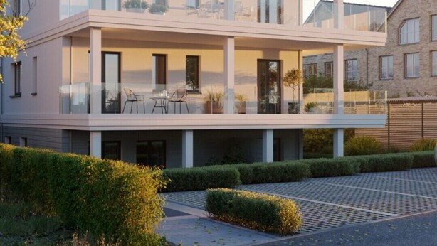 A modern multi-story residential building with balconies, large windows, and a well-maintained garden. - Ferienwohnung Dünenblick App. 1 (Scharbeutz)