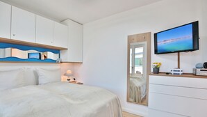 A bedroom with a bed, a TV, a dresser, and a mirror. - Ferienwohnung Dünenblick App. 1 (Scharbeutz)