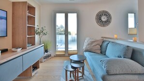 A modern living room with a sofa, a coffee table, a TV, and a wooden cabinet. - Ferienwohnung Dünenblick App. 1 (Scharbeutz)