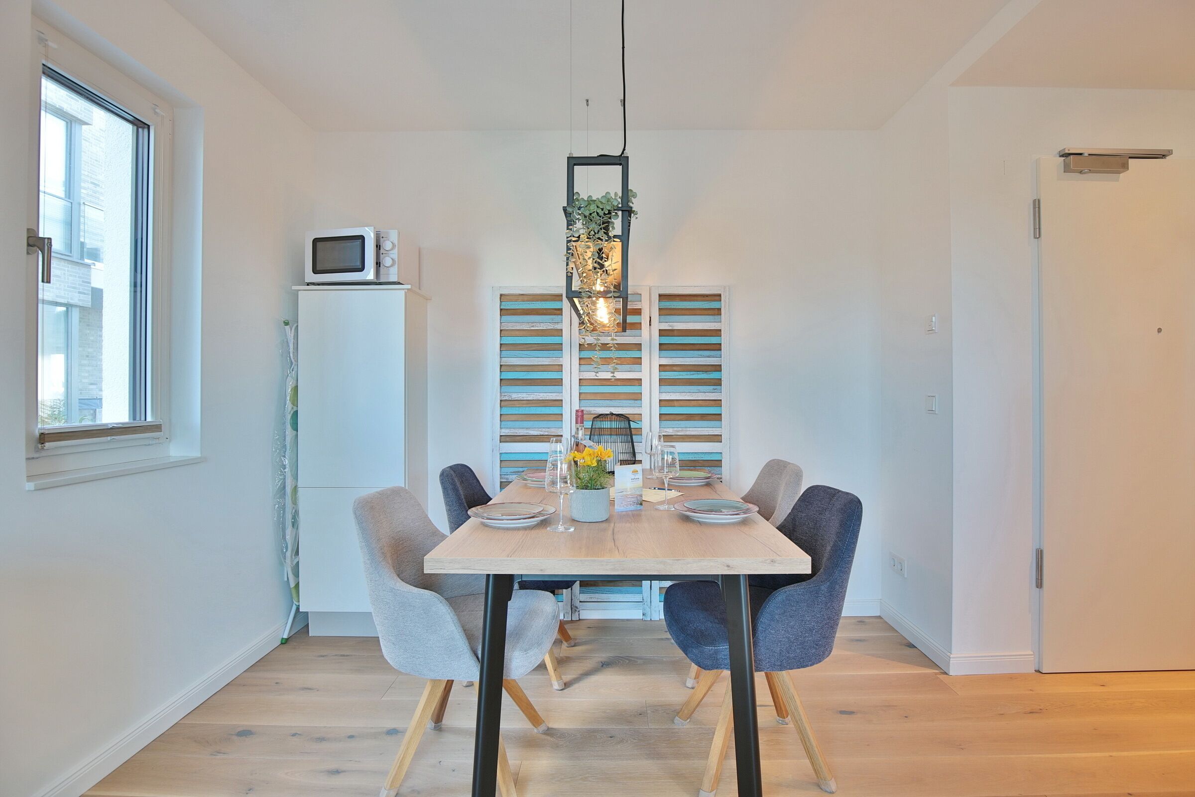 Een moderne eetruimte met een houten tafel, zes stoelen en een hanglamp.