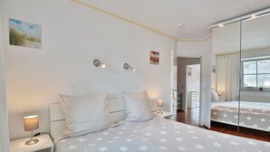 A bedroom with a bed, bedside tables, and a mirror. - Residenz Alte Bergstraße Appartement 14 (Scharbeutz)
