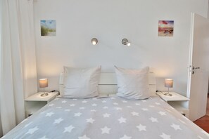 A bedroom with a bed, two bedside tables, two wall-mounted lamps, and two wall art pieces. - Residenz Alte Bergstraße Appartement 14 (Scharbeutz)