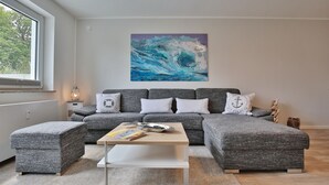 Un soggiorno moderno con un divano modulare grigio, un tavolino bianco e un grande quadro astratto appeso al muro.