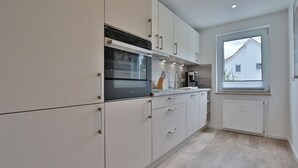 Una cucina moderna con mobili bianchi, forno integrato e una finestra che offre luce naturale.