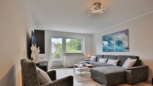 Un soggiorno moderno con un divano angolare grigio, un tavolino da caffè e un oggetto decorativo bianco.