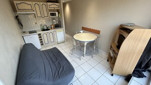 A compact kitchen with a dining area, a small refrigerator, and a microwave. - AGREABLE STUDIO Cabine au coeur de la station 5 bleuets (Besse-et-Saint-Anastaise)