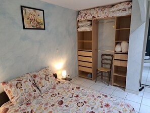 Ein Schlafzimmer mit einem Bett, einem Nachttisch, einem Sessel, einem Kleiderschrank und einem Bild an der Wand.
