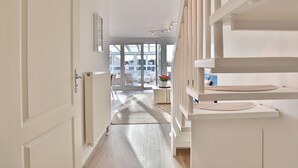 A modern interior with a central hallway leading to a glass door, white walls, and a wooden floor. - Haus Seesand Hansastrasse 7, Penthouse Wohlfühlzeit (Scharbeutz)