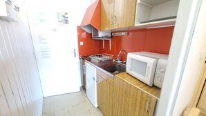 Une cuisine de taille réduite, dotée de meubles en bois, d’un four à micro-ondes et d’un évier.
