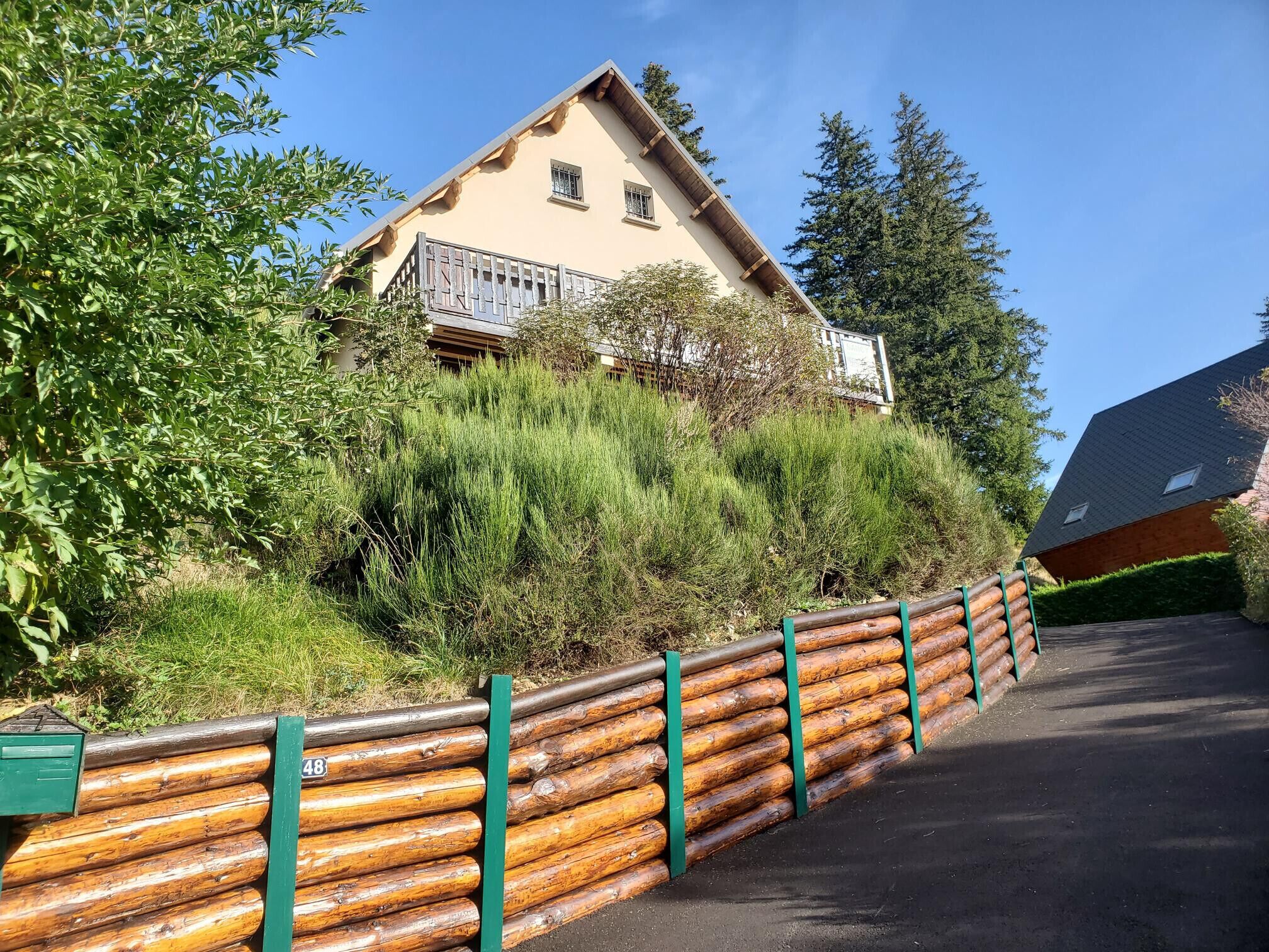 A building with a sloped roof, a balcony, and a surrounding grassy area.