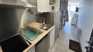 Eine kompakte Küche mit Einbauherd, Spüle und Mikrowelle.