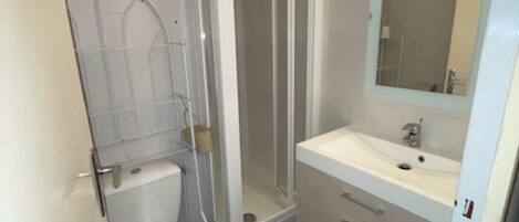 Un baño con inodoro, cabina de ducha y lavabo con espejo.
