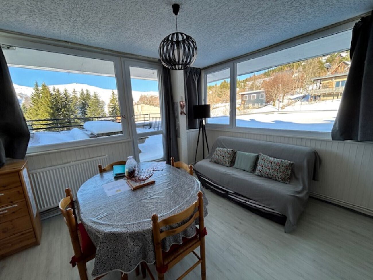 A cozy room with a round table, a sofa, and a window with a view of a snowy landscape.
