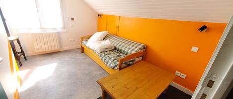 A room with a single bed, a wooden table, and a window.