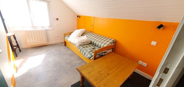 A room with a single bed, a wooden table, and a window.