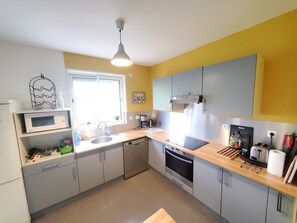 Een moderne keuken met een magnetron, spoelbak, oven en een houten aanrecht.