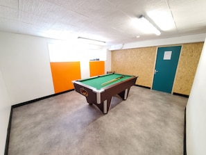 A pool table in a room with a carpeted floor, white walls, and a wooden partition.