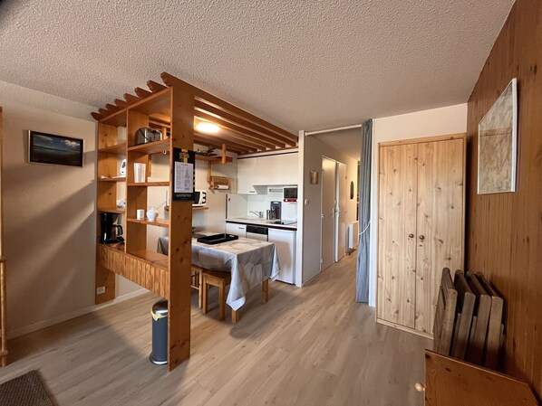 A compact kitchen with wooden shelves, a dining table, and a small island.