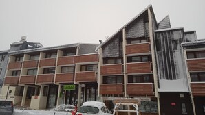 A multi-story building with a sign for S.A.G.A.T. agency, balconies, and a car parked in front.