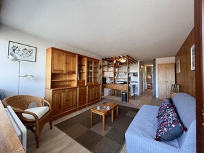 A compact living space with a kitchenette, a dining area, and a seating area with a sofa and a chair.