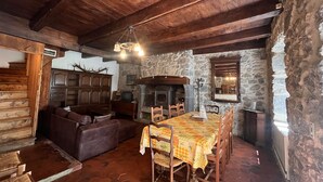 A rustic interior with a stone fireplace, wooden furniture, and a dining table set for four.