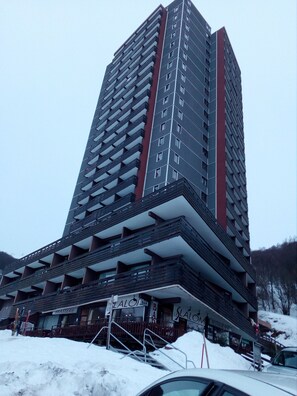 Un immeuble de grande hauteur doté de nombreux balcons et d’un bar situé au rez-de-chaussée.